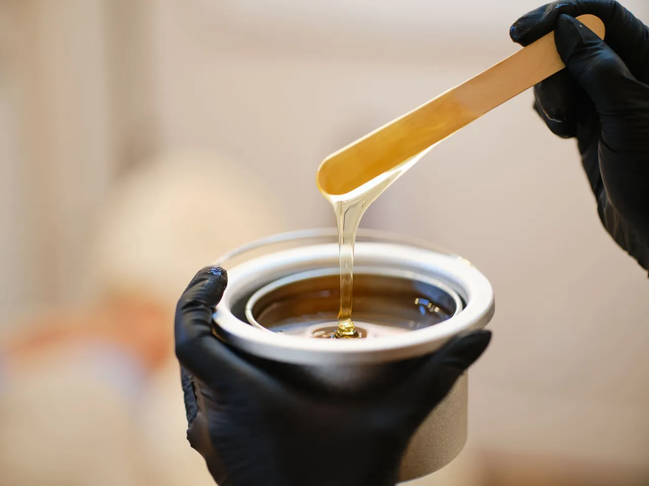 Warm wax dripping from a wooden spatula